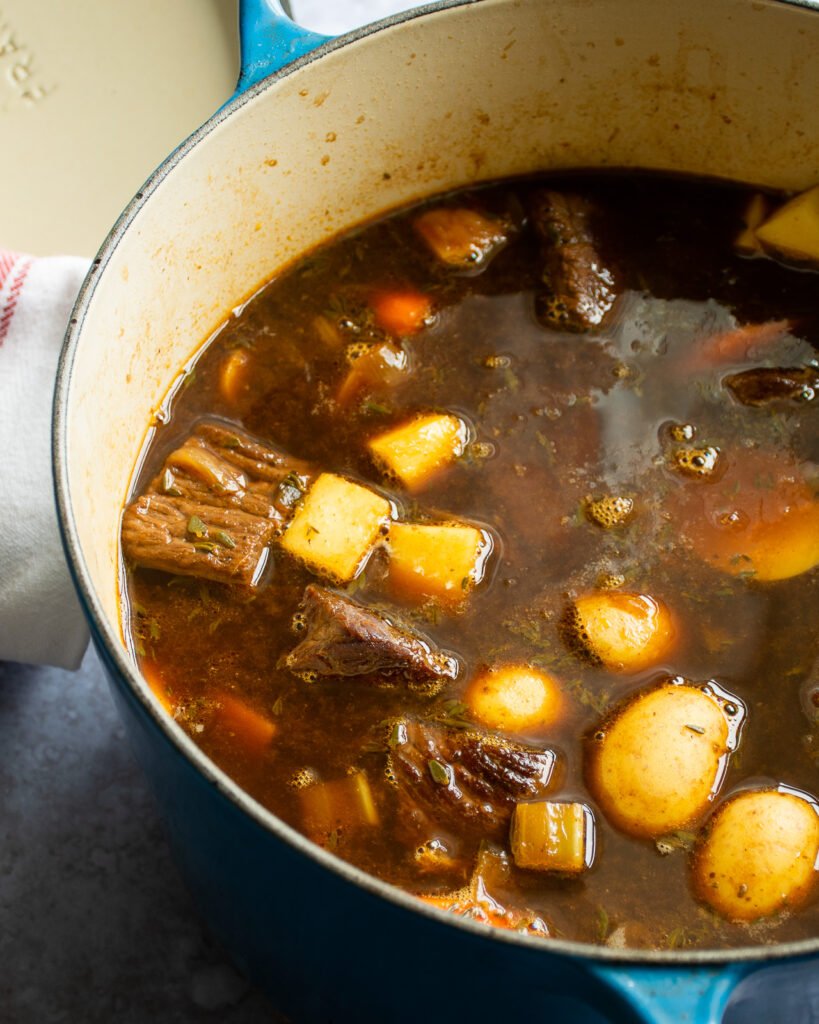 Guinness beef stew in a blue cast iron Dutch oven. 