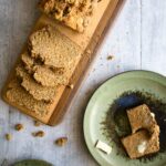 Irish brown soda bread on a cutting board with a few slices made and a side plate with butter and bread.