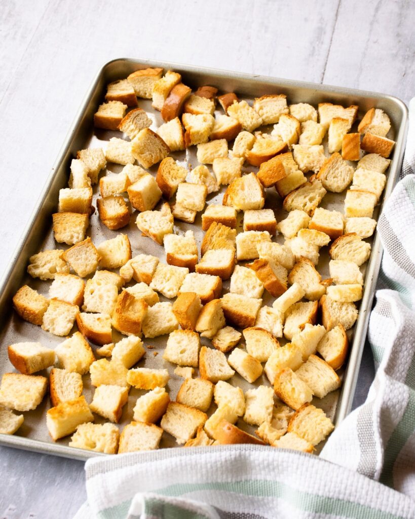 Bread cubes toasting on a sheet pan.