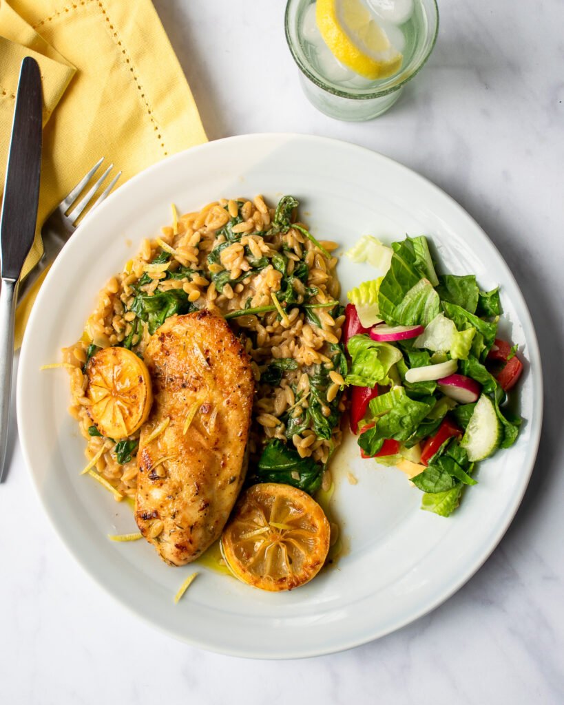 Lemon chicken skillet dinner on aa white plate with a side salad.
