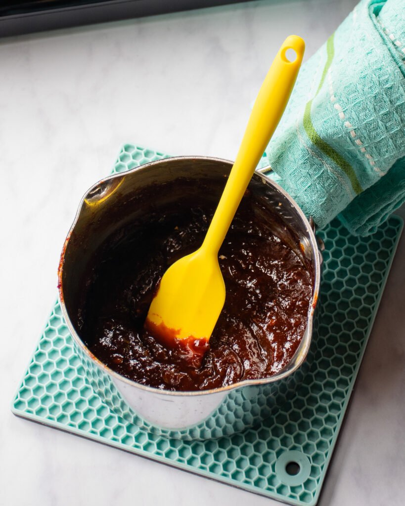 A saucepan with Korean bbq sauce and a yellow spatula.