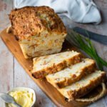 Bacon Cheddar Chive Buttermilk Biscuit Bread on a wooden cutting board with a little dish of butter in the foreground.