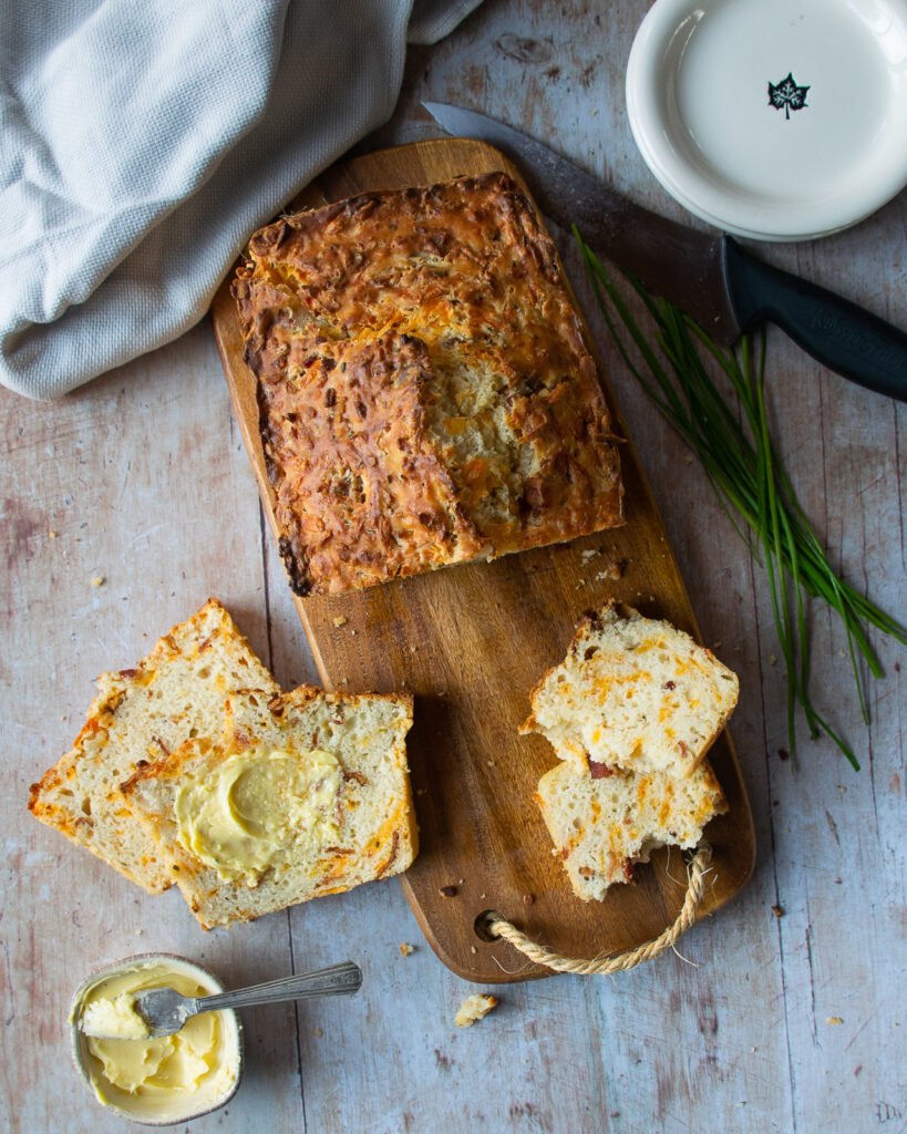 Buttermilk Biscuit Bread on a cutting board with a few slices cut and buttered.