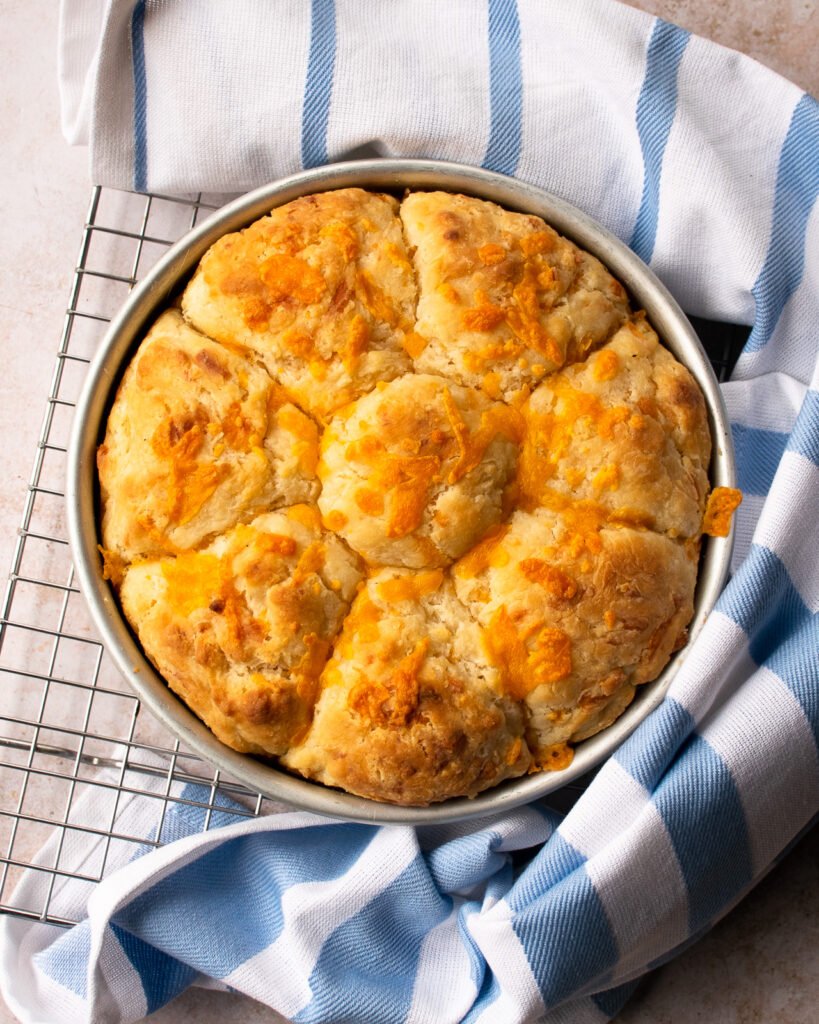 A pan of biscuits on a cooling rack with a blue and white tea towel wrapped around them.