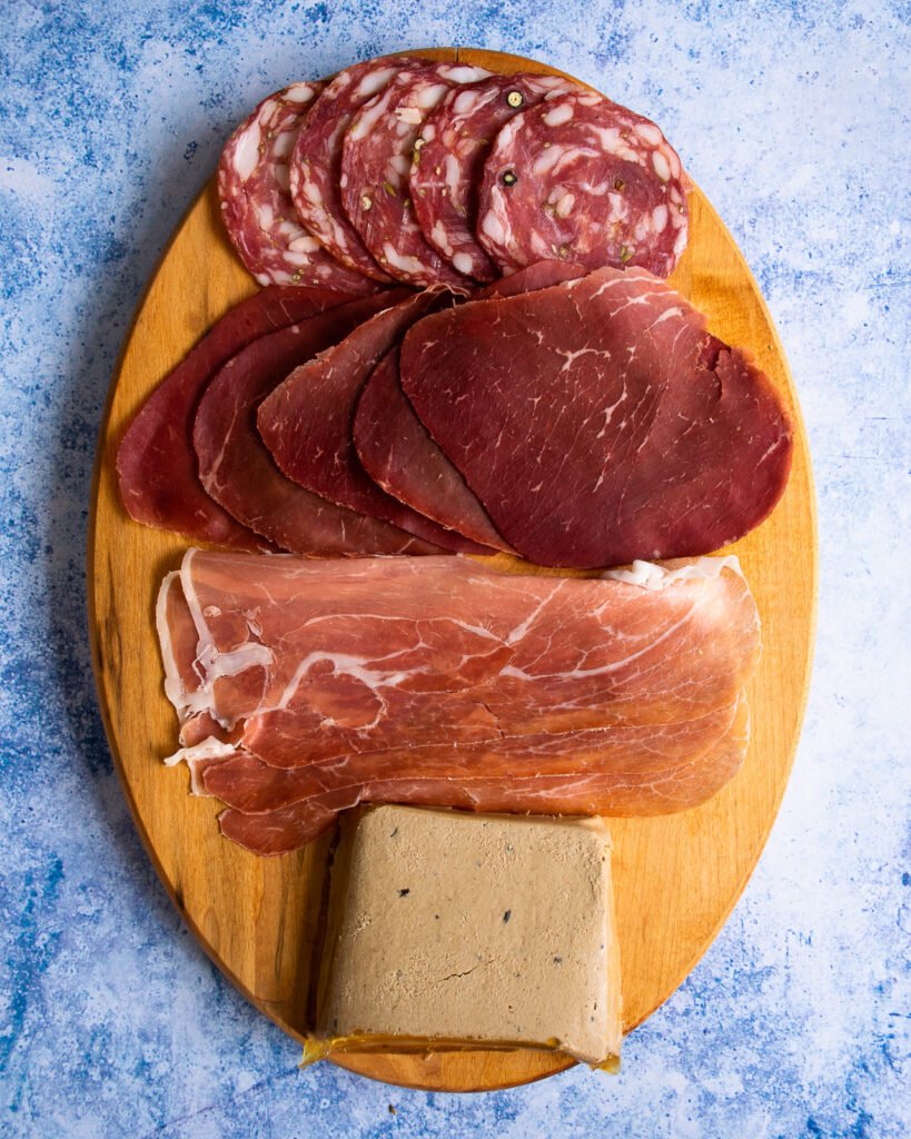 four cured meats on an oval cutting board
