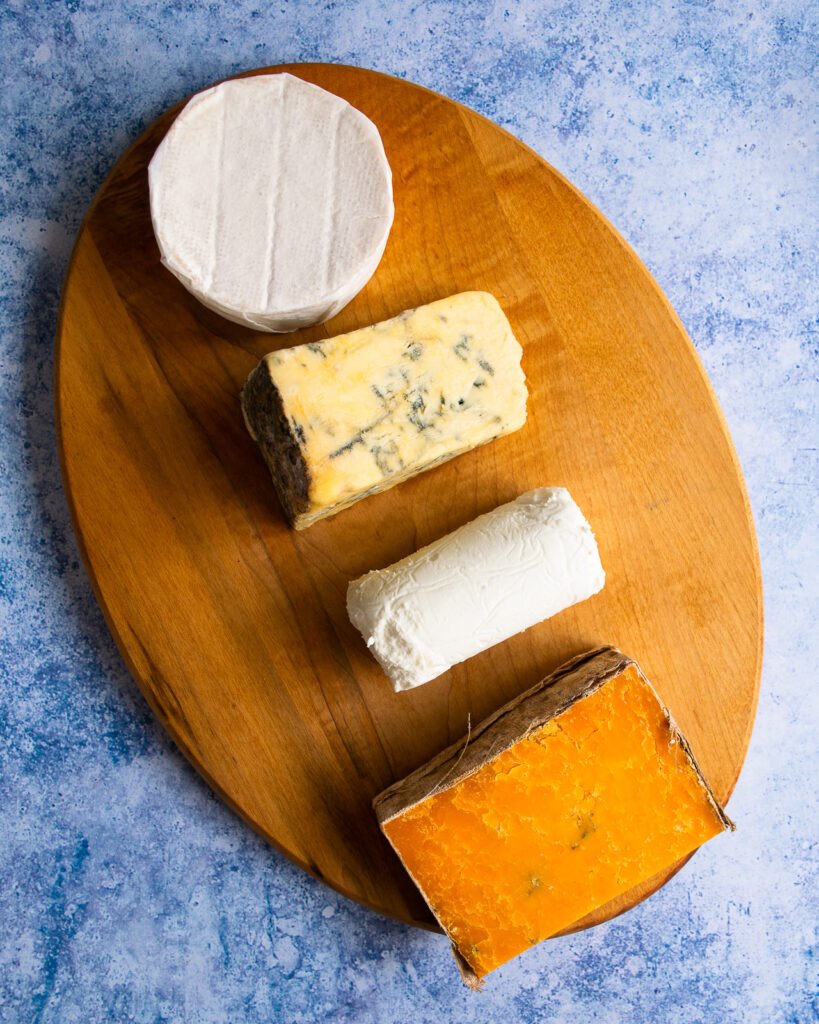 four cheeses on an oval cutting board