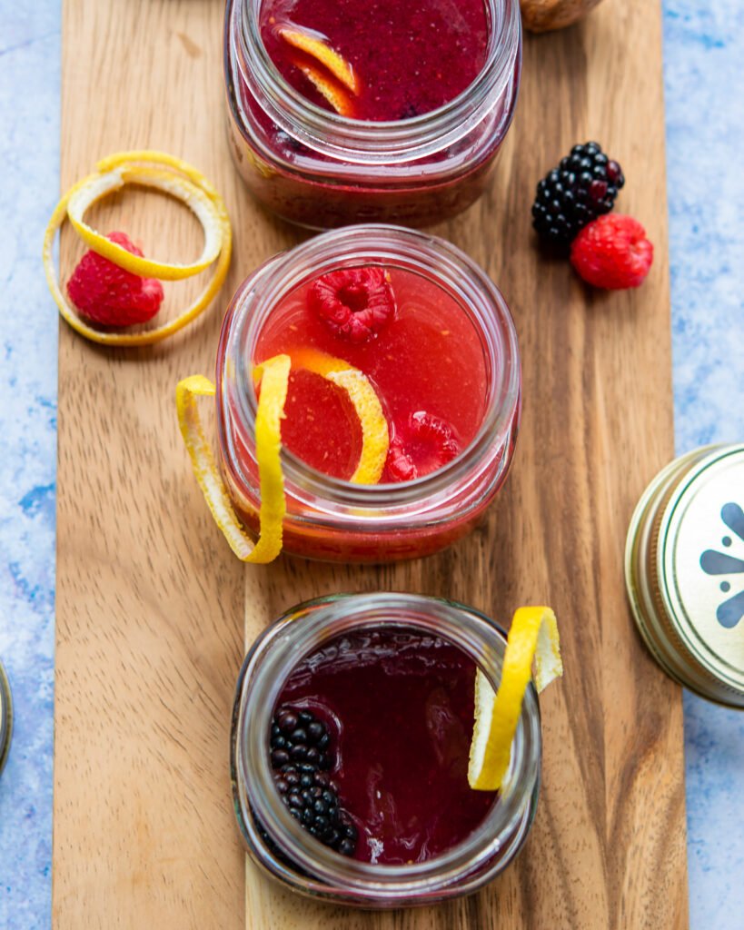 Jam bellinis in mason jars on a wood serving tray.