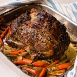 Standing Rib Roast in a roasting pan with vegetables underneath.