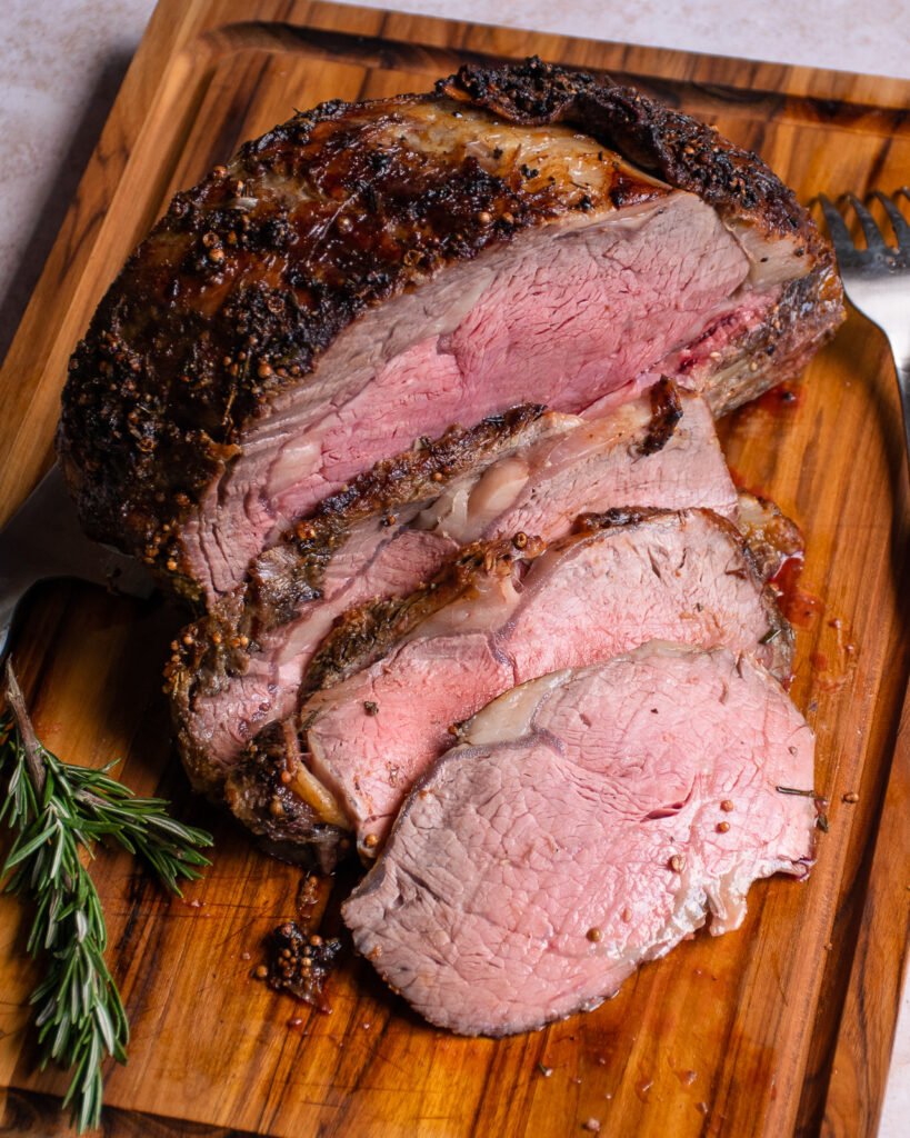 Sliced Standing Rib Roast on a cutting board with a knife.