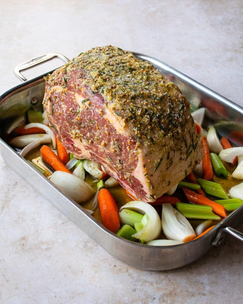A standing rib roast, seasoned in a roasting pan and ready to go into the oven.