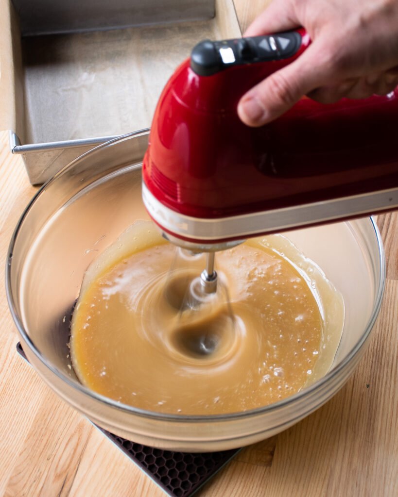 Beaters beating cooled sugar and cream - part of making sucre a la creme.