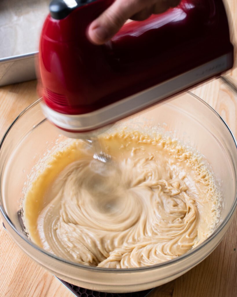 Beaters beating cooled sugar and cream - part of making sucre a la creme.