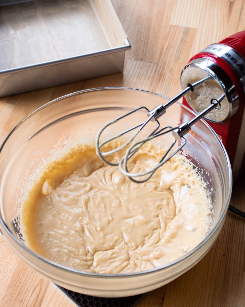 A hand mixer resting over a bowl of sucre a la creme.