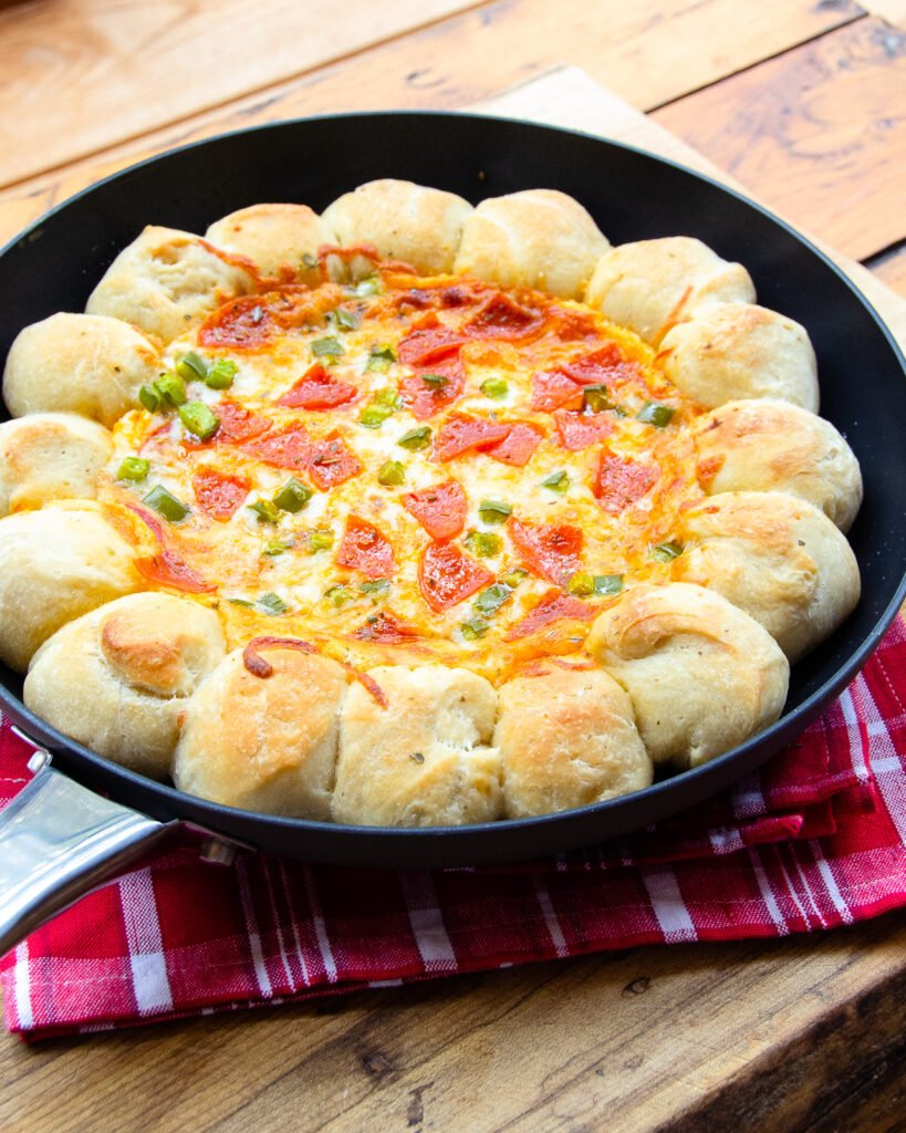 Skillet Pizza dip on a red checkered napkin  on a wooden table.