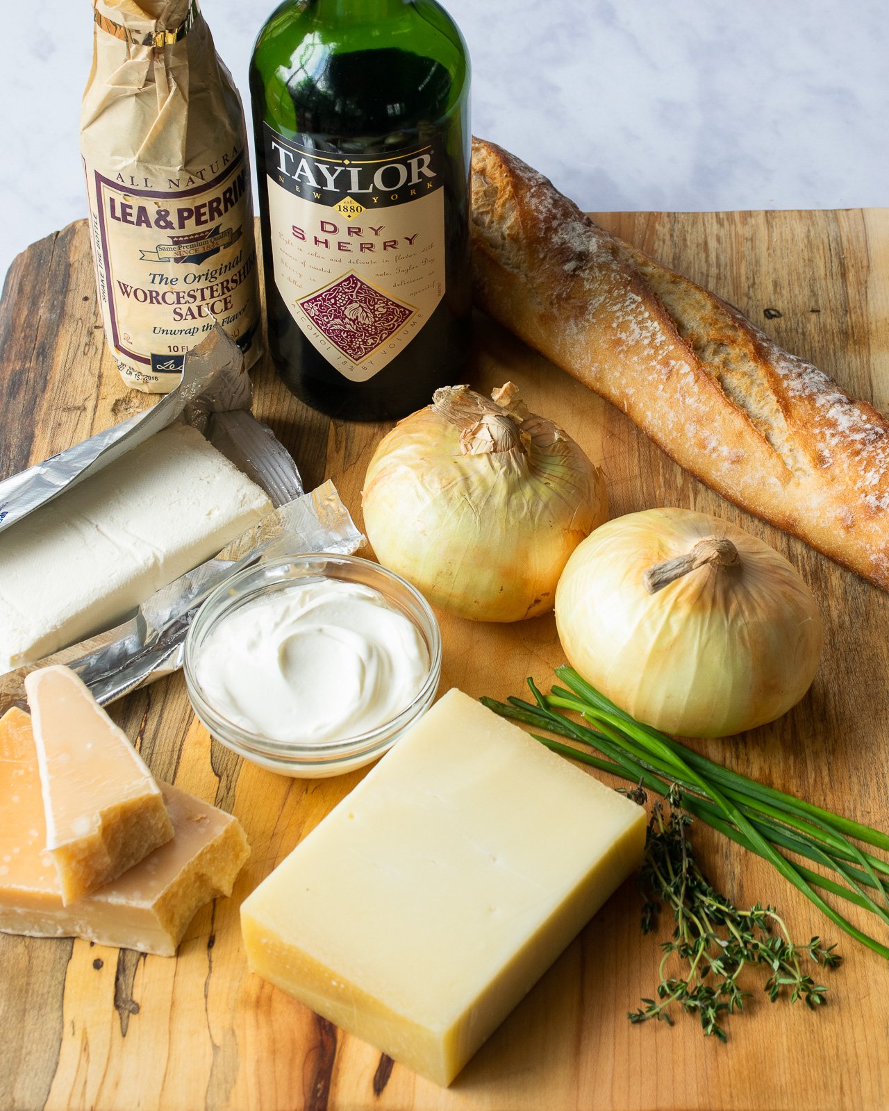 INgredients on a wooden board - Worcestershire sauce, dry sherry, cream cheese, sour cream, Parmesan cheese, Gruyère cheese, onions and chives.