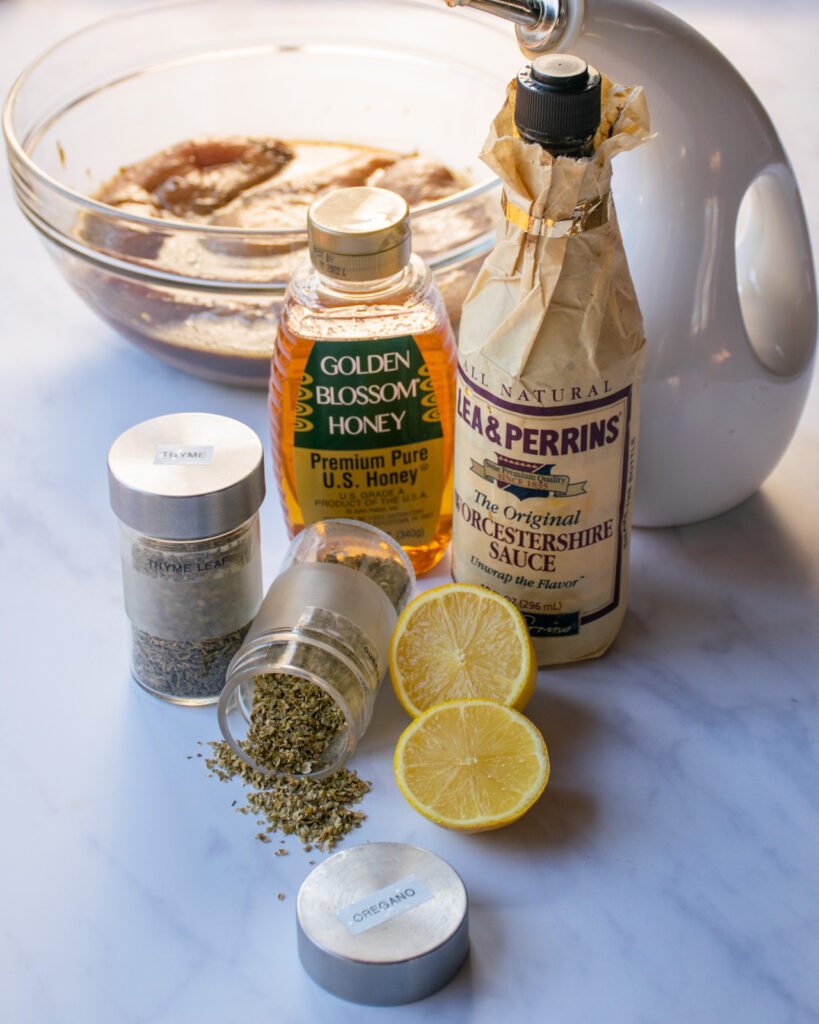 Ingredients for marinated chicken breasts - honey, worcestershire sauce, lemon, spices, oil, salt and pepper.
