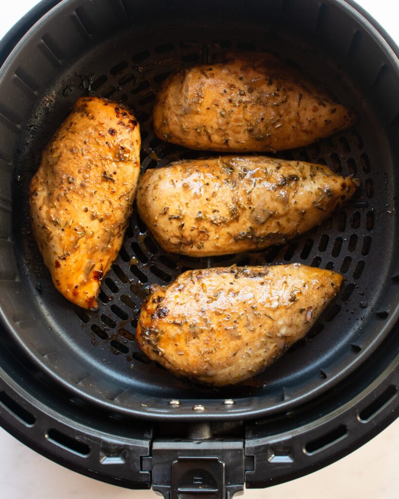 Chicken breasts in the basket of an air fryer.