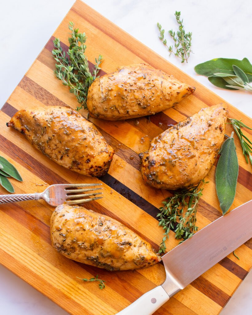 Air fried chicken breasts cooked and on a cutting board with a knife and fork.