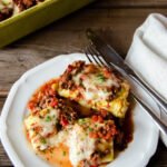 A Portion of ricotta stuffed cabbage shells on a white plate on a wooden table.