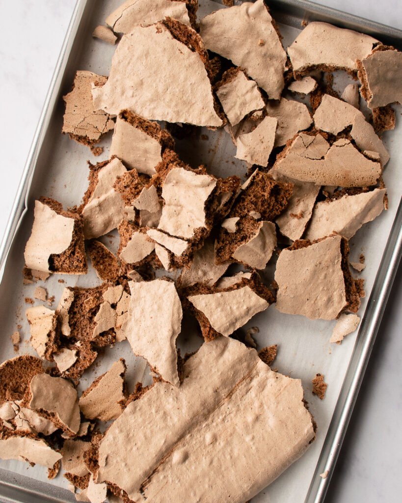 Chocolate meringue broken up on a baking sheet.