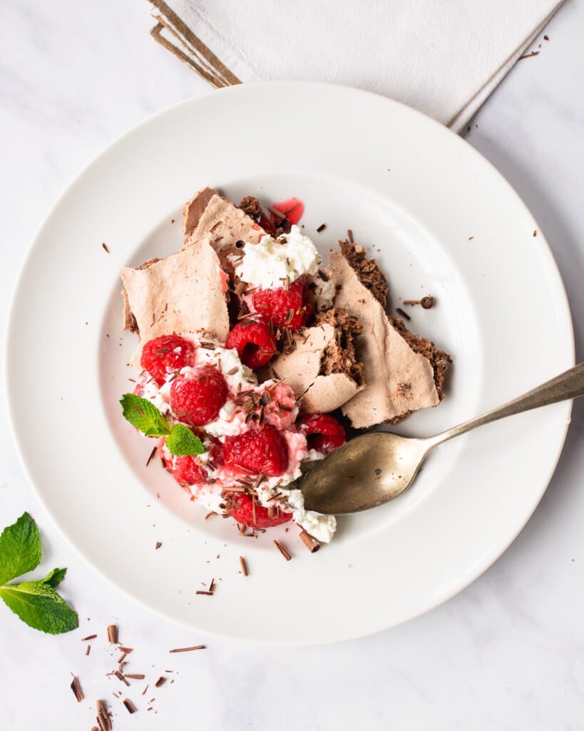 Chocolate Eton Mess on a white plate with aa spoon
