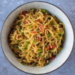 A bowl of sesame noodles on a grey counter.