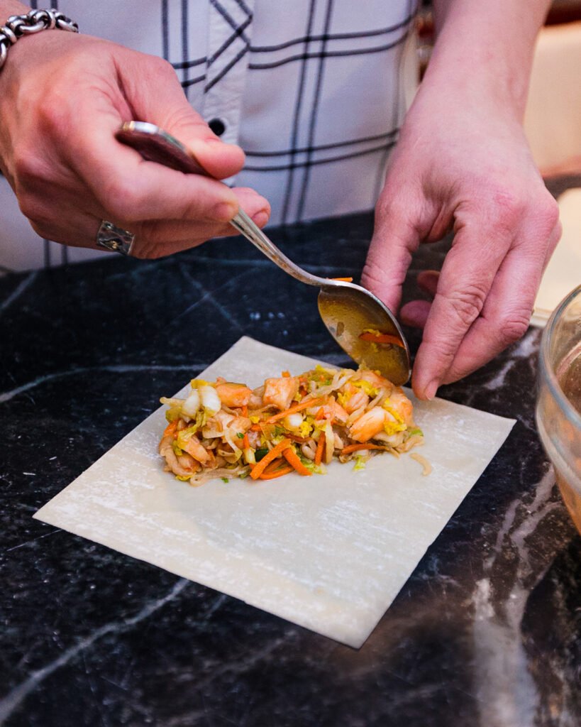 First step in making shrimp egg rolls - putting the filling on an egg roll wrapper.