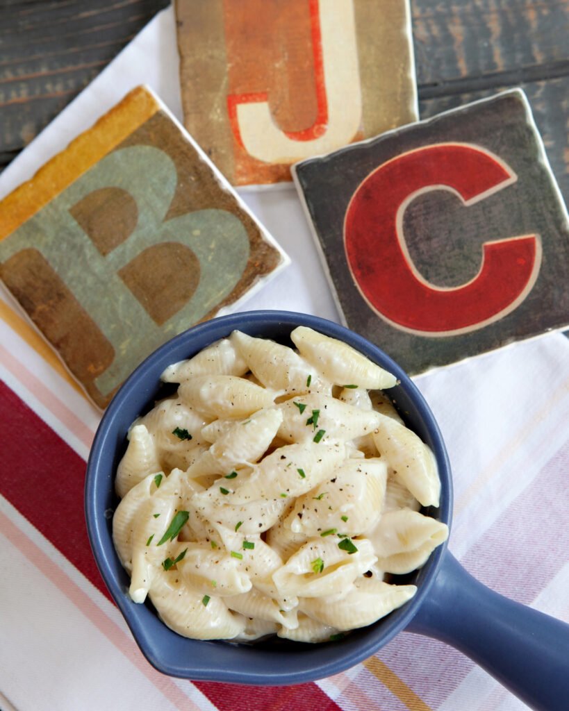 a blue dish of macaroni and cheese on a white napkin with the letters B, J and C.