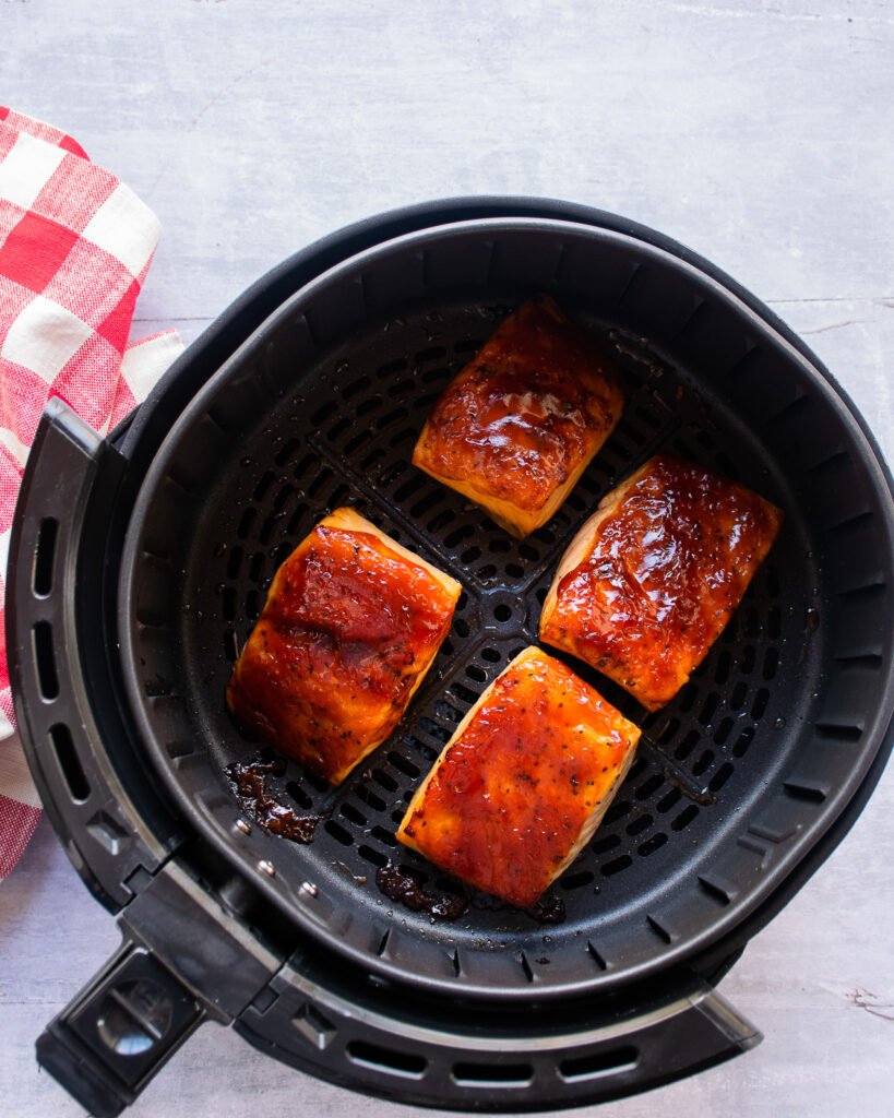 Balsamic BBQ Salmon in an air fryer with a red checkered napkin nearby.