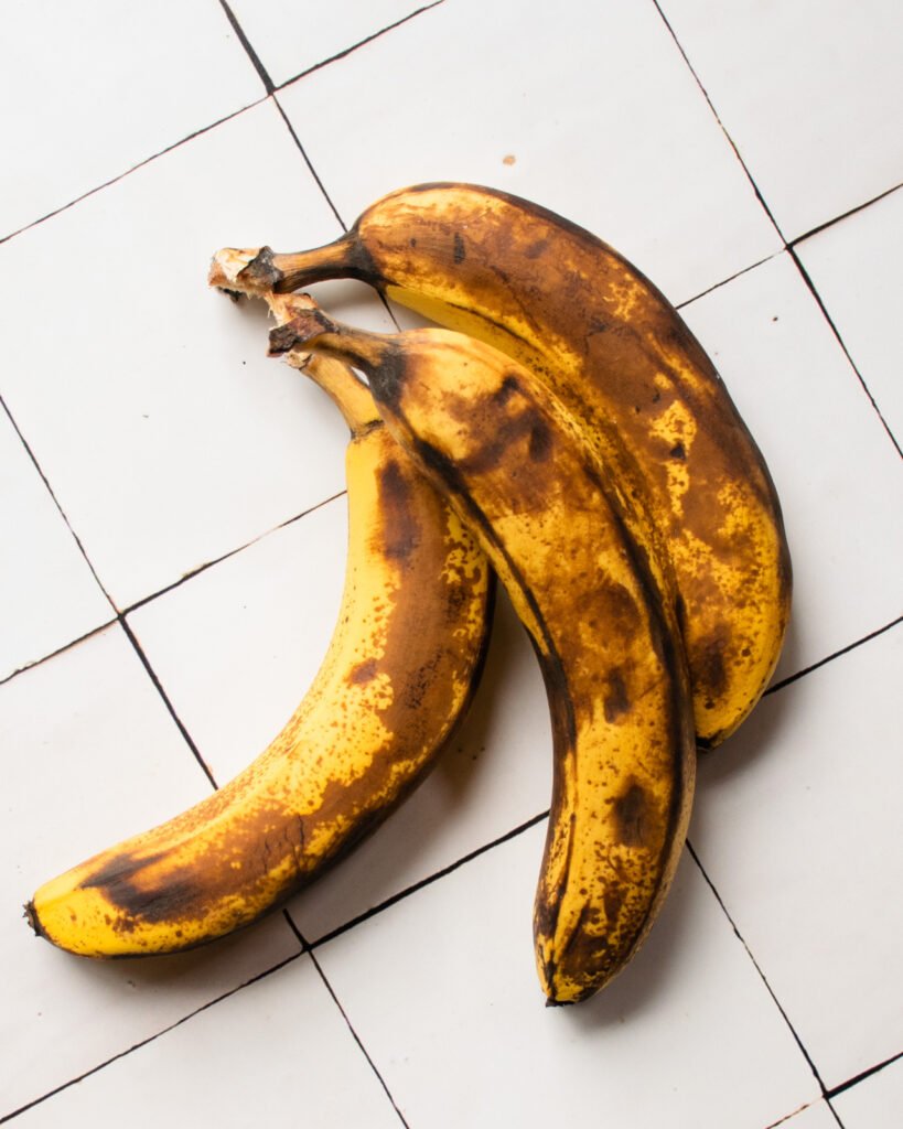 Three over-ripe bananas on a tile countertop.