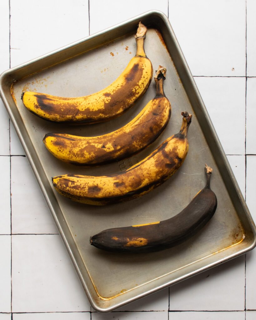 Four bananas on a cookie sheet - one with black peel.