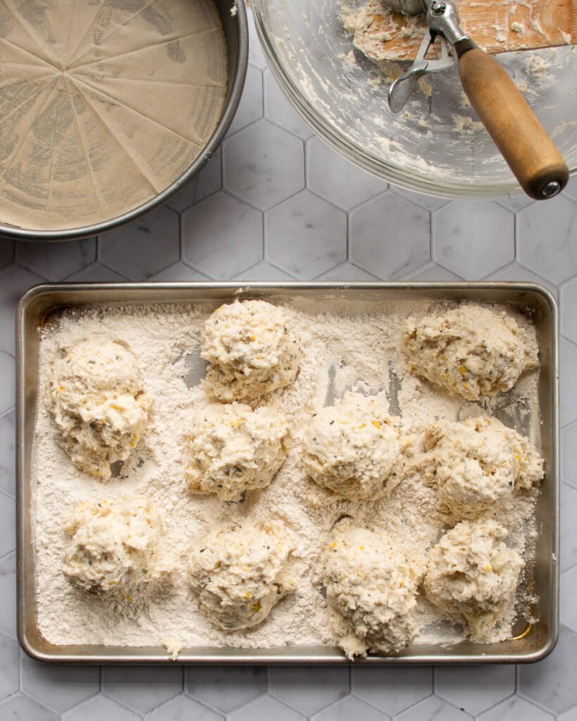 Buttermilk biscuit batter on a sheet pan coated in flour.