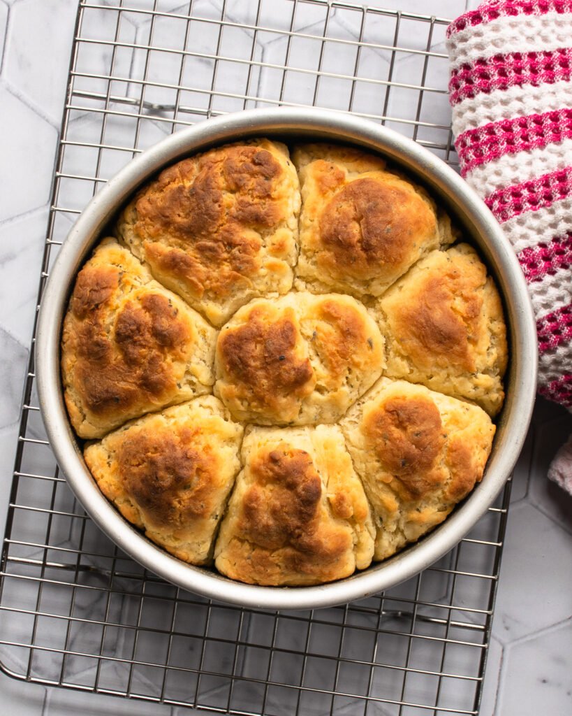 Lemon Rosemary Buttermilk Biscuits baked in a round cake pan on a cooling rack.