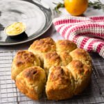 Lemon Rosemary Biscuits on a cooling rack with a lemon, rosemary and a red and white striped towel in the background.