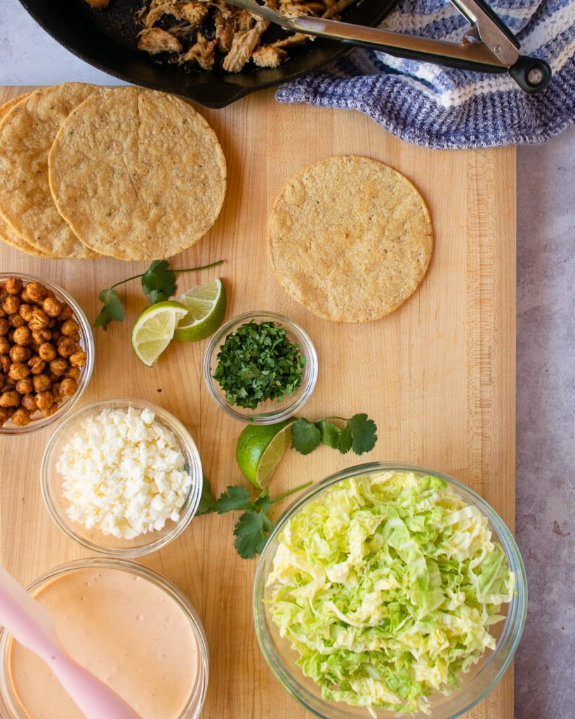 All the components of chicken tostadas on a cutting board.
