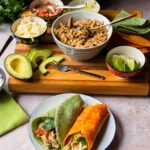Two chicken tacos on a plate in front of all the taco fixings.