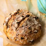 No Knead Fruit and Nut Bread on brown parchment paper with a turquoise towel in the background.