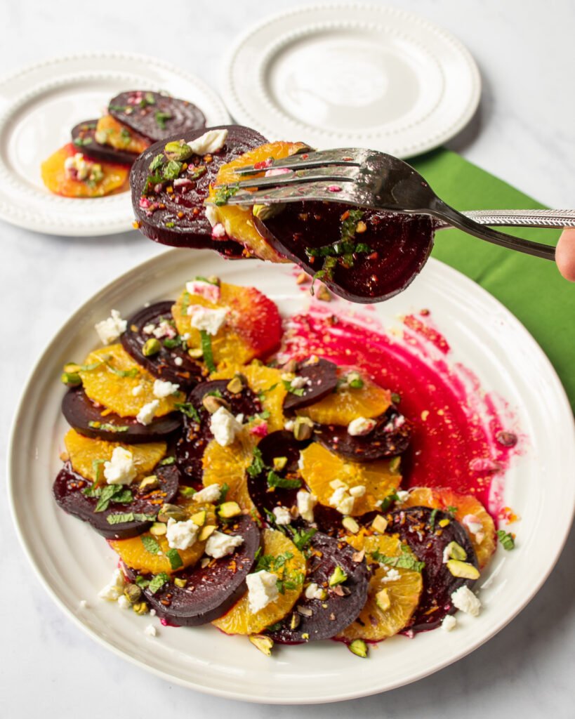 A spoon and fork serving beet and orange salad.
