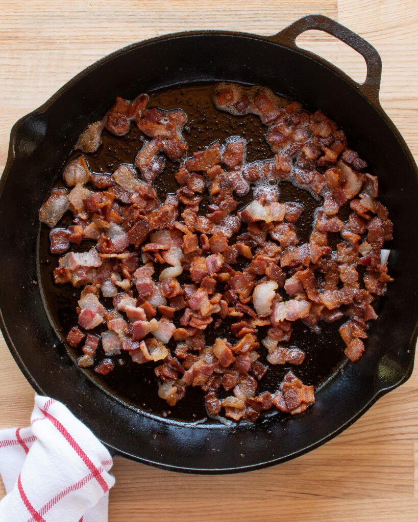 Bacon cooking in a cast iron skillet.
