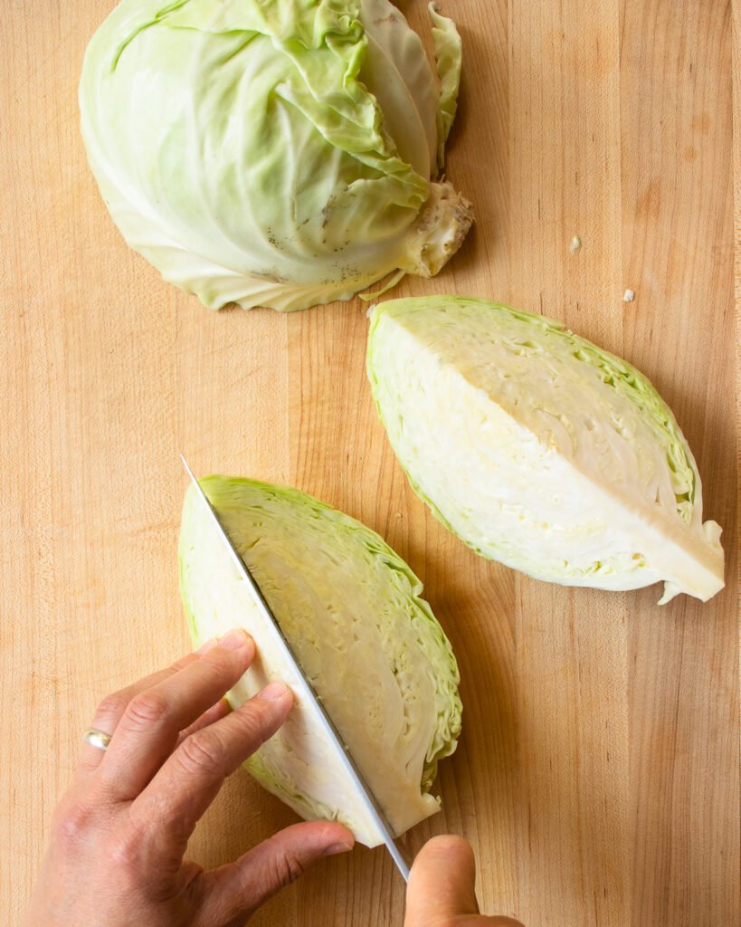 Cutting a quarter head of green cabbage into wedges.