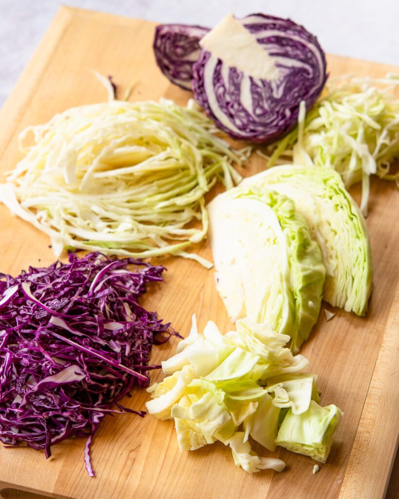 Different cuts of cabbage on a cutting board.