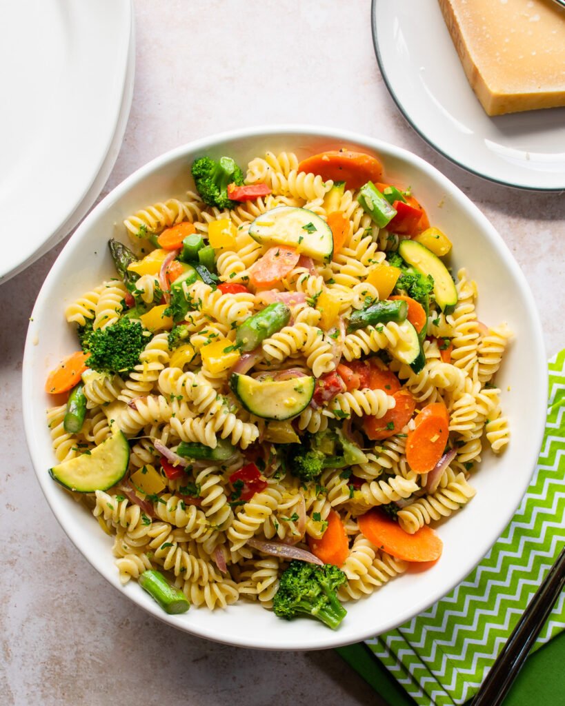 Pasta primavera in a big white bowl with a green napkin on the side.