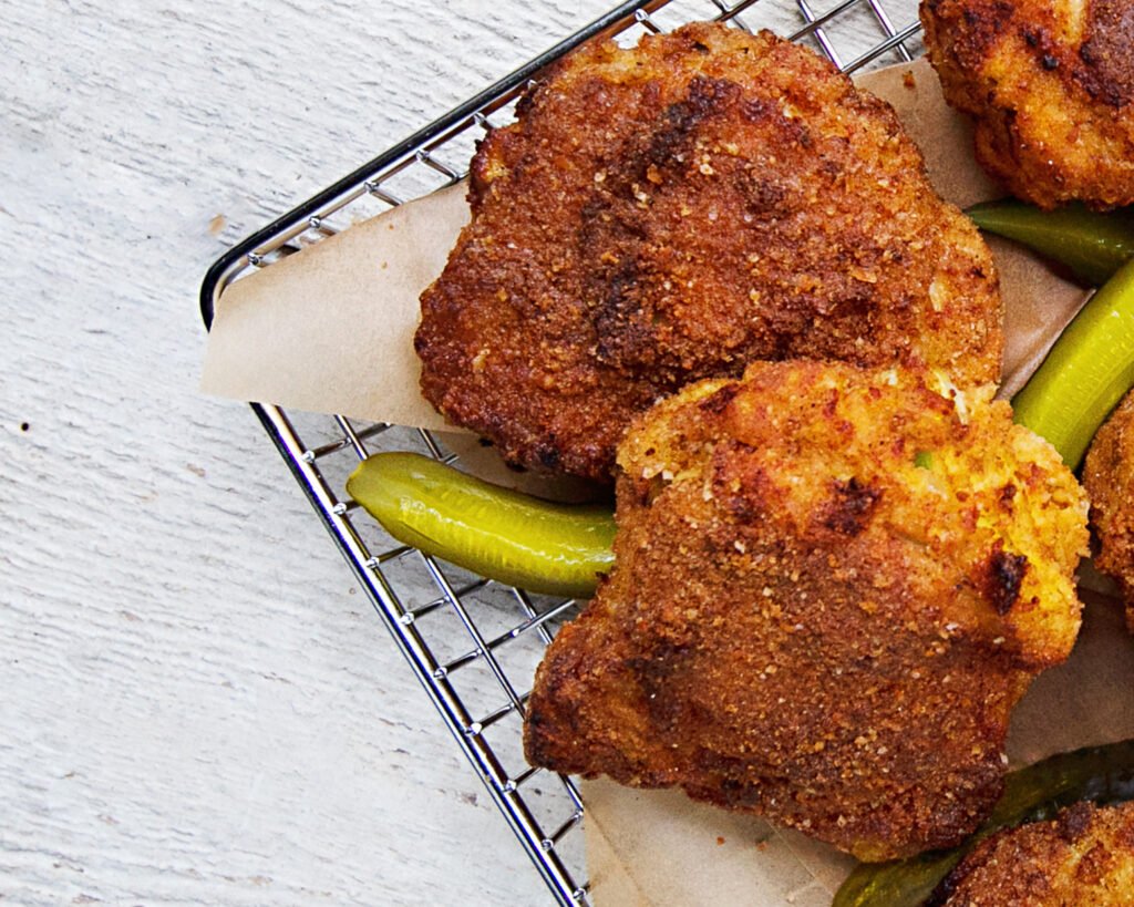 pickle brined fried chicken in a wire basket with pickle spears.