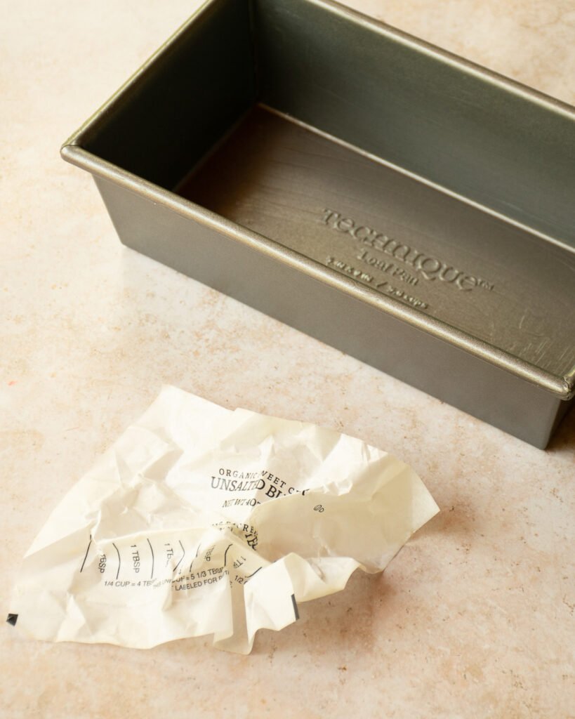 A loaf pan and a butter wrapper on a counter.