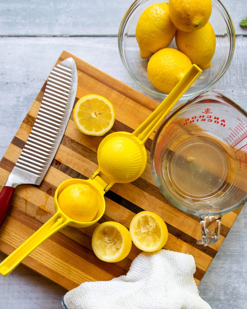 Lemons being squeezed with a press on a cutting board.