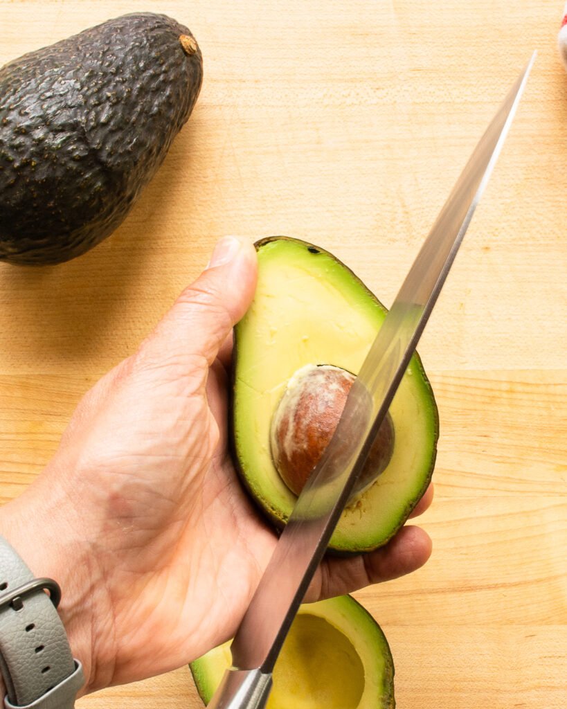 A knife stuck in an avocado seed.