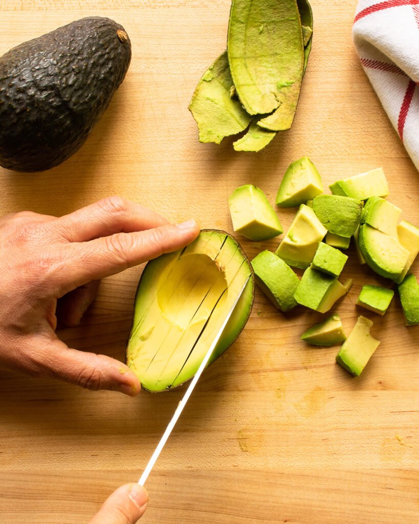 A knife slicing into half an avocado.