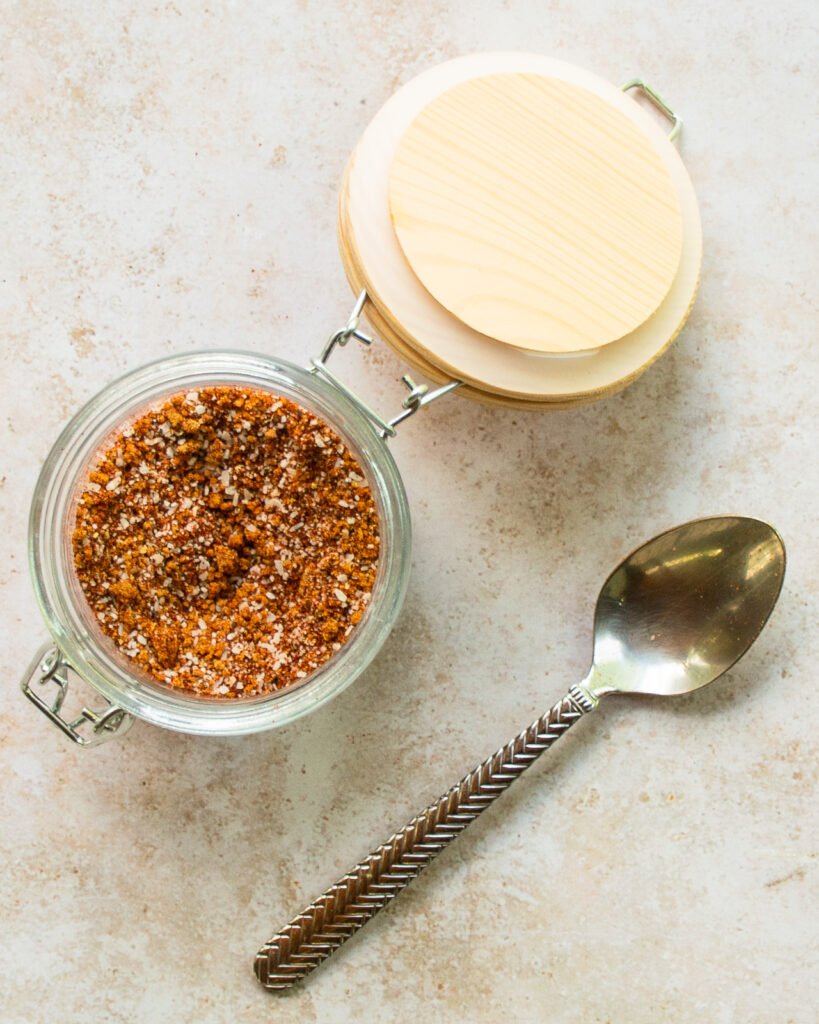 Best dry rub spice mix in a glass jar with wooden lid and spoon.
