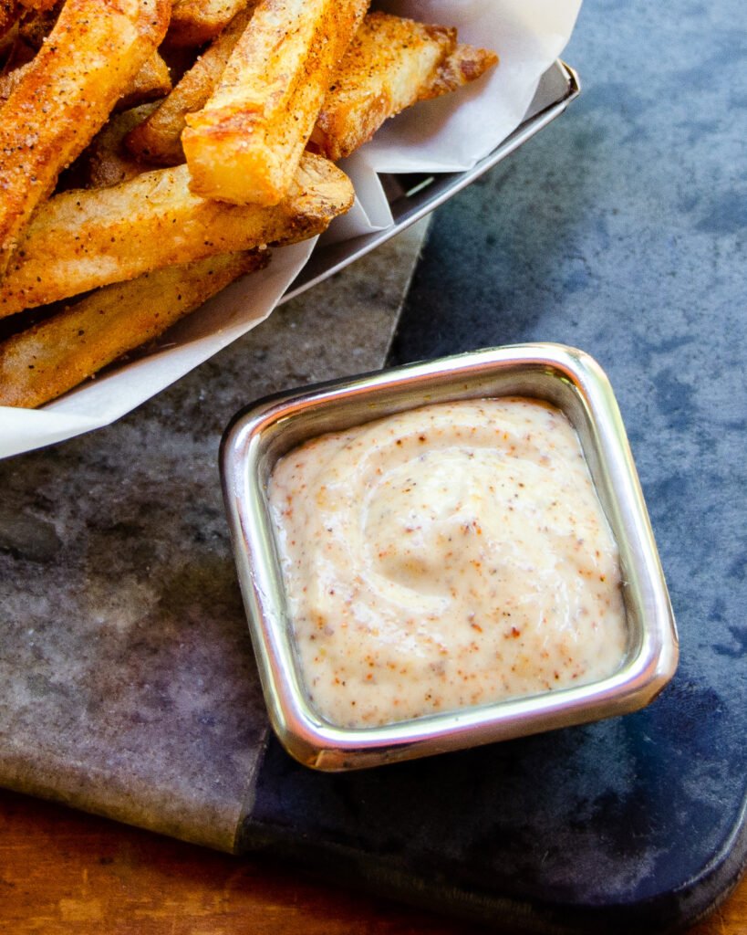 Close up of creole dipping sauce with cajun fries next to it.