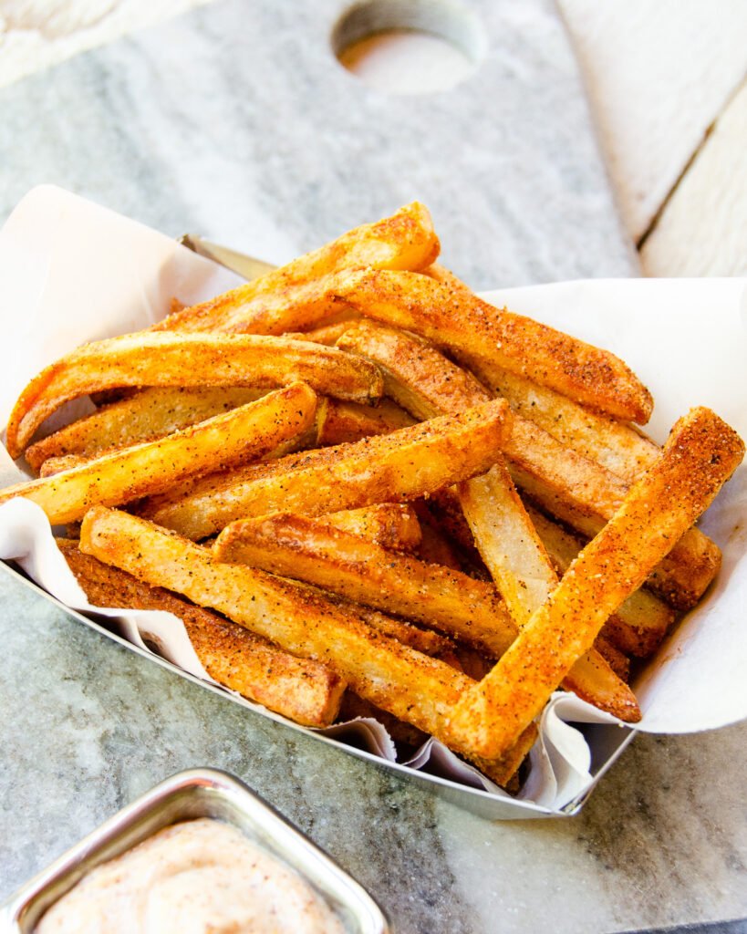 Close up of cajun fries in a paper-lined french fry tray.